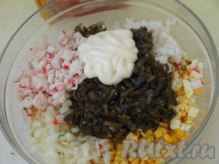 Смешиваем крабовые палочки, рис, яйца, лук, морскую капусту и консервированную кукурузу, добавляем майонез. Немного кукурузы оставьте для оформления салата.
