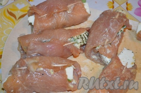 Начиная с узкой стороны, свернуть пласт куриного филе в рулет, края скрепить зубочисткой.