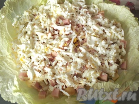 Поверх лука и грибов выложить нарезанный кубиками балык, сделать сеточку из майонеза и посыпать натёртыми яичными белками.