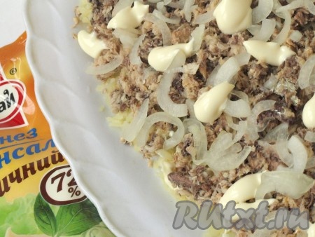С рыбных консервов сливаем масло и разминаем вилкой, выкладываем поверх картофеля. Лук, нарезанный полукольцами, маринуем в уксусе, промываем холодной водой. А затем выкладываем лук поверх консервов, смазываем слегка майонезом.
