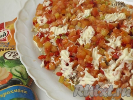 Из болгарского перца сразу вырезаем язычки огня, оставшийся перец и помидоры нарезаем мелкими кубиками. Смешиваем порезанные помидоры и перец, выкладываем следующим слоем, солим, смазываем майонезом.