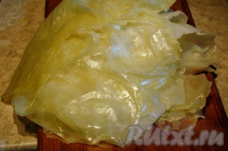 Минут через 15 после закипания воды достать кочан и осторожно снять первые листья, ставшие достаточно мягкими. Кочан с оставшимися листьями снова отправить в кастрюлю и продолжить варить. Минут через 10 снять ещё листья, ставшие достаточно мягкими. И так далее продолжать отваривать кочан капусты, пока не останется совсем немного некрупных листьев, которые не подойдут для приготовления голубцов (листья, не подошедшие для приготовления голубцов, отложите в сторону, они нам понадобятся в дальнейшем для запекания голубцов в духовке). Остудить листья, снятые с кочана, которые подходят для приготовления голубцов.