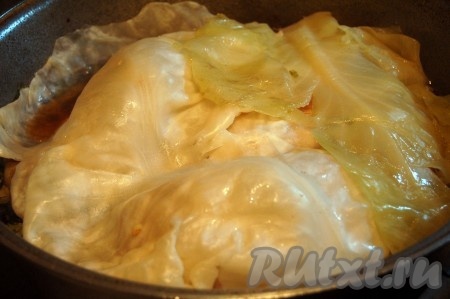 Пока обжариваются голубцы, взять форму для запекания, выложить предварительно отваренные листья капусты, которые не подошли для формирования голубцов. В форму, застеленную капустными листами, выложить обжаренные голубцы. Постепенно обжарить все голубцы, затем переложить их в форму. В отдельную ёмкость выложить томатную пасту, влить 200-250 миллилитров воды, перемешать, посолить по вкусу получившийся томатный соус. Влить томатный соус в форму с обжаренными голубцами, по желанию посыпать сушёной (или нарезанной свежей) зеленью, сверху прикрыть отваренными капустными листьями, которые по каким-то причинам были забракованы при формировании голубцов (порваны). Отправить форму в горячую духовку.