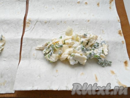 Лаваш нарезать на полоски размером 20 сантиметров на 15 сантиметров. Ближе к узкому краю полоски из лаваша, отступив 1-2 сантиметра от краёв лаваша, выложить 1-2 столовых ложки сырной массы.