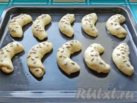 На противень, смазанный растительным маслом, выложить рогалики на расстоянии друг от друга. Смазать рогалики сверху яйцом, посыпать семечками (или кунжутом). Оставить на 30 минут, чтобы рогалики подошли. Духовку разогреть до 180 градусов.