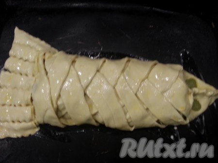 Тесто закрываем сверху. Голову рыбки делаем, скрепляя верхние края теста, а тело закрываем из полосок, как косичку. В конце делаем хвостик. Глазки можно сделать из маслин или каких-то ягод, я солёный огурчик поставила. Перекладываем слоеный пирог с рыбой и грибами на противень, смазанный маслом, смазываем пирог яйцом и ставим в разогретую духовку минут на 20 при умеренной температуре.