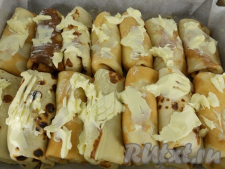 Таким образом сформировать все блинчики с творогом. Выложить их боком в форму для запекания, которую нужно застелить пергаментом и хорошо смазать сливочным маслом (масло не жалеть). Сверху блинчики также смазать сливочным маслом (побольше). Можно блинчики выкладывать в 2 слоя.
