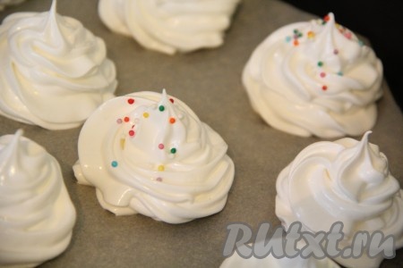 Посыпать меренги цветной посыпкой. Поставить противень в холодную духовку и выставить температуру 50-60 градусов. Меренги в домашних условиях нужно выпекать при невысокой температуре, а вот время выпечки следует увеличить. Час выпекаем при 60 градусах, а далее увеличить температуру до 100 градусов. Выпекаем ещё 1 час. Затем выключить духовку и оставить меренги на 1-2 часа в духовке.