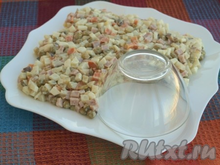 Подготовить плоскую тарелку, лучше квадратную. На угол поставить чашку или подходящую ёмкость. Салат выложить в форме русского кокошника. Подровнять со всех сторон.
