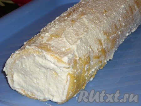 Оставшимся творожно-масляным кремом смазать бисквитный рулет сверху и по бокам, отправить в холодильник для пропитки на пару часов.