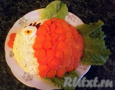 Морковку порезать тонкими кружочками и выложить в виде чешуи на салат. Из двух кружочков моркови сделать губы золотой рыбки, установить глаз из яйца, зрачок – черный перец. Ресницы можно сделать из маслин. Дать салату настояться в холодильнике минимум 2 часа.
