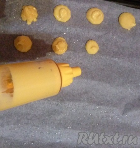 Застилаем противень бумагой для выпечки и смазываем бумагу растительным маслом. С помощью кулинарного шприца или ложкой выкладываем тесто на противень. Между профитролями оставляйте расстояние, так как при выпечки они увеличатся в размерах. Ставим профитроли в разогретую до 180 градусов духовку на 40-50 минут. Во время выпечки ни в коем случае не открывайте дверцу духовки, иначе тесто осядет. Как только профитроли зарумянятся, вынимаем их из духовки.
