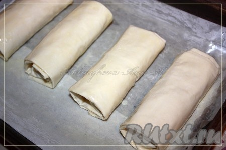 Готовые рулеты уложить на пекарскую промасленную бумагу и сверху еще раз их промазать маслом.