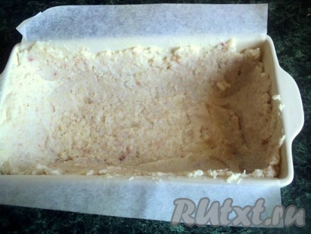 Форму размером 20х10 см застелить бумагой для выпечки, смазать растительным маслом.&nbsp; Выложить половину рыбно-рисовой массы и равномерно распределить ее по дну и стенкам формы.
