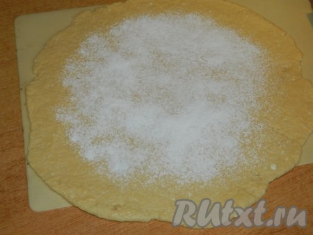 Творожное тесто, собравшееся в ком, делим на 2 равные части (мы будем выпекать 2 галеты со сливами). Противень застилаем бумагой для выпечки (или силиконовым ковриком). На застеленный противень перекладываем одну часть теста и раскатываем в круг (очень тонко раскатывать не нужно). Если раскатывать тесто не на противне, то нежное раскатанное тесто с начинкой будет достаточно сложно перенести на противень. Середину круга присыпаем 1 столовой ложкой крахмала (крахмал не даст сливам сделать низ галеты влажным).