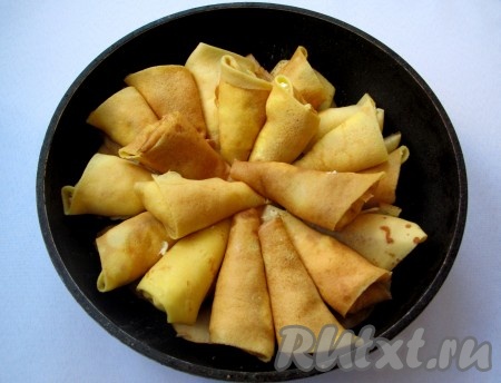 На сковороду положите кусочки сливочного масла и растопите. Затем выложите конвертики, накройте крышкой и тушите на маленьком огне 20-25 минут. Периодически поднимайте крышку, переворачивайте блинные конвертики и следите, чтобы они не подгорели. Возможно, потребуется подлить чуть-чуть водички или добавить ещё масла.