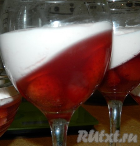 В креманки или бокалы положить немного ягод клубники. Разлить готовое желе и оставить застыть под наклоном. На застывшее желе выложить творожный слой.