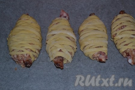 Теперь делим фарш на 4 части (по количеству ребрышек). Берем ребро и формируем вокруг него котлету из фарша. Далее оборачиваем полосочками теста в хаотичном порядке. Выкладываем веретена из мяса и теста на противень, застеленный пекарской бумагой.
