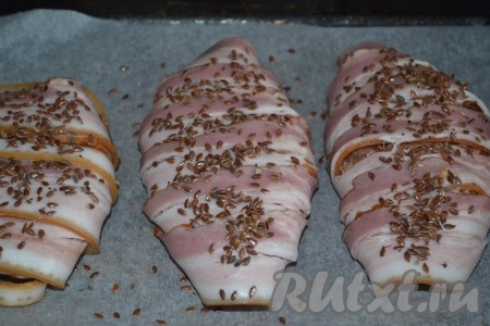 Выкладываем готовые изделия на противень, застеленный пергаментом, и присыпаем семенами льна.
