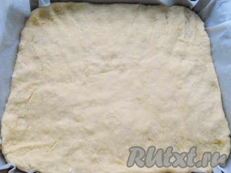 Добавляя небольшими порциями муку, учитывайте, что тесто должно получиться мягким, нежным, не липнущим к рукам и столу. Форму диаметром 23-25 сантиметров с высокими бортами застелить пергаментной бумагой. Тесто раскатать по размеру формы или растянуть его руками прямо в форме. Прикрыть форму с тестом пищевой плёнкой и оставить для подхода в тёплом месте на 1 час.
