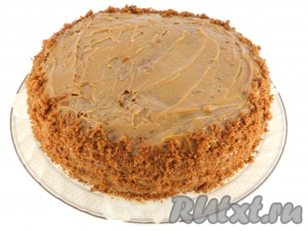 Выложить третью часть коржа. Верх и бока смазать варёной сгущёнкой. Бока обсыпать подготовленной крошкой.