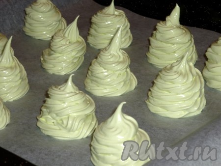 Переложить взбитые белки в кондитерский мешок и отсадить на застеленный пергаментом противень в виде ёлочек.