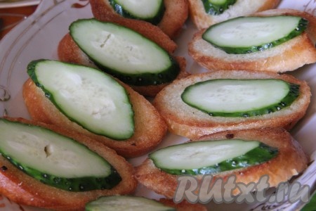 По одному тонкому кружочку огурца выложить на каждый бутерброд.
