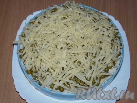 Перед подачей на стол украсить верх салата тёртым сыром, убрать пищевую плёнку, аккуратно снять бортики. Сыр можно натереть на крупной или на мелкой тёрке, как вам больше нравится.
