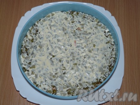 Далее выложить слой маринованных огурчиков, разровнять и слегка смазать майонезом.
