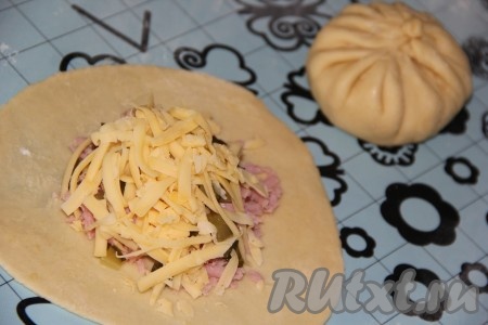 Наше дрожжевое тесто увеличится в объёме раза в 2, его нужно хорошо обмять. Разделить тесто на небольшие части. На припылённой мукой поверхности раскатать каждую часть теста в лепёшку, на середину выложить часть натёртой ветчины, немного нарезанных огурчиков (можно обойтись и без огурцов), посыпать частью натёртого сыра и плотно скрепить края теста в виде "мешочка" (как на фото). Аналогично в виде "мешочка" сформировать все булочки с ветчиной и сыром.
