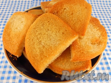 Батон нарезать на ломтики, каждый ломтик разрезать пополам. Обжарить ломтики на хорошо разогретой сковороде с добавлением растительного масла на среднем огне до румяности с одной стороны. Дать остыть.