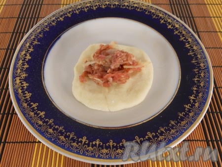 Тесто скатать в жгут и порезать небольшими кусочками. Скатать каждый в шарики и сформировать лепешки. В середину лепешки поместить 1 столовую ложку фарша.
