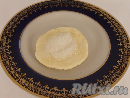 Из теста скатать две колбаски, нарезать каждую колбаску на кусочки размером с грецкий орех (или чуть больше). Раскатать каждый кусочек в лепёшку (не тонко). В середину каждой лепёшки всыпать 0,5 чайной ложки сахара.