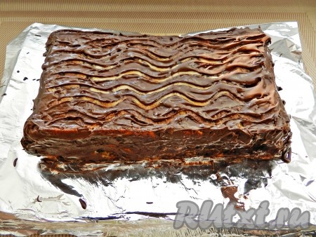 Растопить шоколад в микроволновке. Остывшую творожную запеканку покрыть шоколадной глазурью. Затем оставить запеканку в холодильнике на ночь, где она уплотнится и будет хорошо нарезаться на кусочки.
