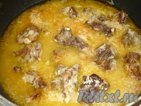 Добавляем кипяток, чтобы вода была выше уровня риса, ставим на сильный огонь, доводим до кипения, затем уменьшаем огонь и тушим 20-30 минут до готовности риса.