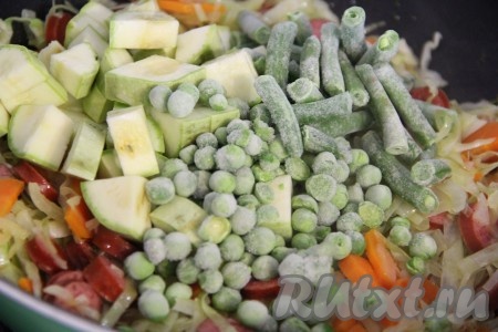 Кабачок нарезать на средние кусочки. Перец очистить от семян, нарезать средними кубиками. Добавить кабачок, фасоль, перец и горошек к овощам с колбасой. Всё хорошо перемешать и тушить под крышкой 5-7 минут, периодически помешивать.&nbsp;
