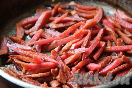 Пока отваривается чечевица, копчёную колбасу нужно нарезать соломкой и обжарить на сковороде на растительном масле в течение 3-4 минут, периодически помешивая, на среднем огне.