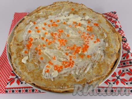 Каждый блин смазать сырной массой, сверху выложить немного красной икры.
