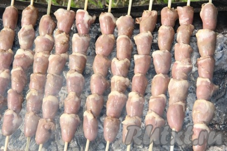 Подготовить мангал, в нём должны быть раскалённые седые угли, но прямого огня быть не должно. Поместить на мангал куриные сердечки на шпажках. Жарить шашлык с двух сторон до готовности (примерно по 8 минут с каждой стороны).