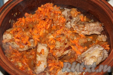 В сковороду, в которой обжаривали ребра, поместить мелко рубленный лук и натертую морковь. Обжарить овощи, периодически помешивая, до золотистого цвета. В приготовленную зажарку возвратить мясо, добавить томатный сок и тушить на медленном огне 3-5 минут.
