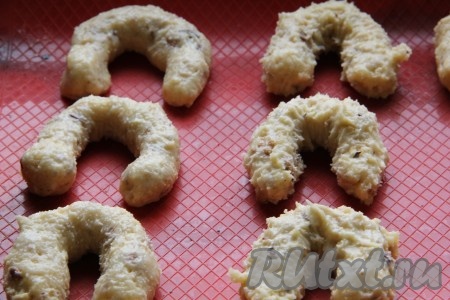 По истечении времени от теста отщипывать небольшие кусочки (размером немного больше грецкого ореха). Из каждого кусочка сформировать подковку и выложить её на противень, застеленный ковриком для выпечки (или пергаментной бумагой). Поставить противень в разогретую духовку и выпекать печенье из грецких орехов минут 15-20 при температуре 180 градусов.