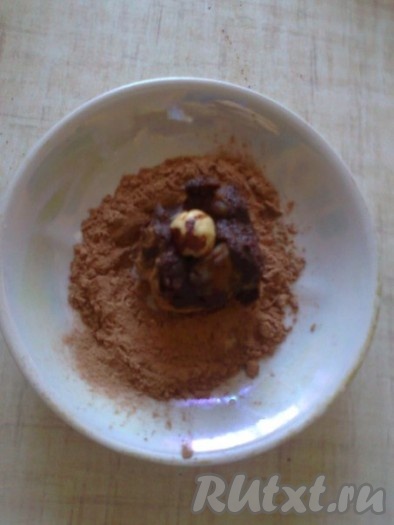 Ганаш остудить и убрать в холодильник. Этот вариант ганаша застывает значительно дольше (около 2-3 часов) и получается более мягким по вкусу и структуре. Чайной ложкой набираем немного ганаша, кладём в тарелку с какао и пудрой, сверху выкладываем орешек.