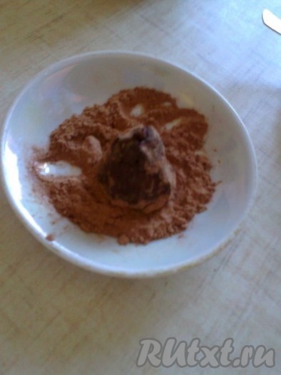 Если ганаш сильно застыл в холодильнике, оставьте его при комнатной температуре, пока он не станет достаточно пластичным, чтобы можно было формировать из него трюфели. Какао и сахарную пудру просеять на тарелку. Чайной ложкой набирать немного ганаша, класть в тарелку с какао и сахарной пудрой, формировать небольшие шарики или пирамидки, обмакивая пальцы в смесь какао и пудры.