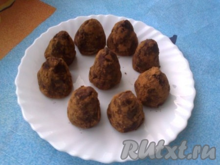 Формируем пирамидку, обмакивая пальцы в смесь какао и пудры. Аналогично формируем трюфели с орехами из оставшегося ганаша, выкладываем на тарелку и убираем в холодильник.