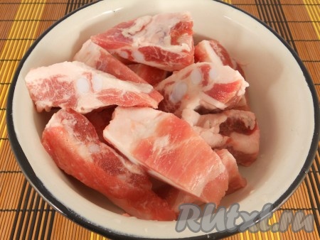 Свиные рёбрышки помыть, обсушить и нарезать. Зубчики чеснока очистить.