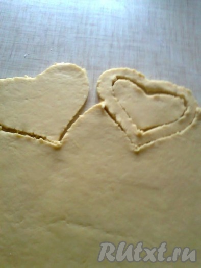 Раскатать тесто скалкой в прямоугольник (толщина 6-7 мм). Вырезать формочкой или ножом печенье в виде сердечек. Половину печенья оставить целым, а во второй половине печенья вырезать середину выемкой или ножом тоже в виде сердечка.