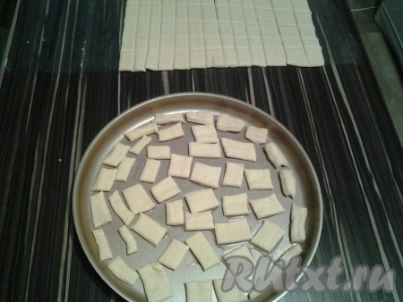 Разрезать слоёное тесто на маленькие квадратики. Положить кусочки слоеного теста на противень, смазанный растительным маслом, и поставить в разогретую духовку на 5-7 минут при температуре 180 градусов до появления лёгкой корочки (наблюдать, чтобы низ кусочков не подгорел).
