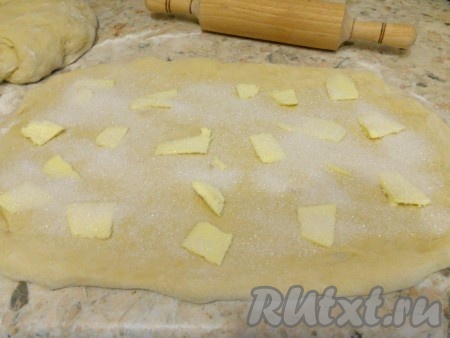 Разделить тесто на 2 части, каждую - раскатать в прямоугольник. Разложить по поверхности теста тонкие кусочки сливочного масла (или смазать размягченным маслом), посыпать щедро сахаром (на половину теста - 4 столовые ложки).
