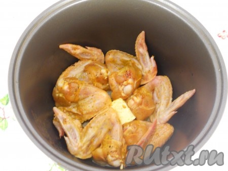 В чашу мультиварки влить растительное масло, выложить подготовленные крылышки.