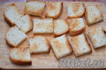 Обжарить нарезанные кусочки батона на сухой (или слегка смазанной маслом) сковороде с двух сторон до золотистого цвета.  Остудить кусочки батона. Ещё можно подсушить батон в тостере.
